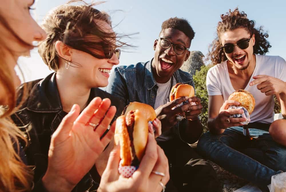 Group of friends sitting, eating burgers