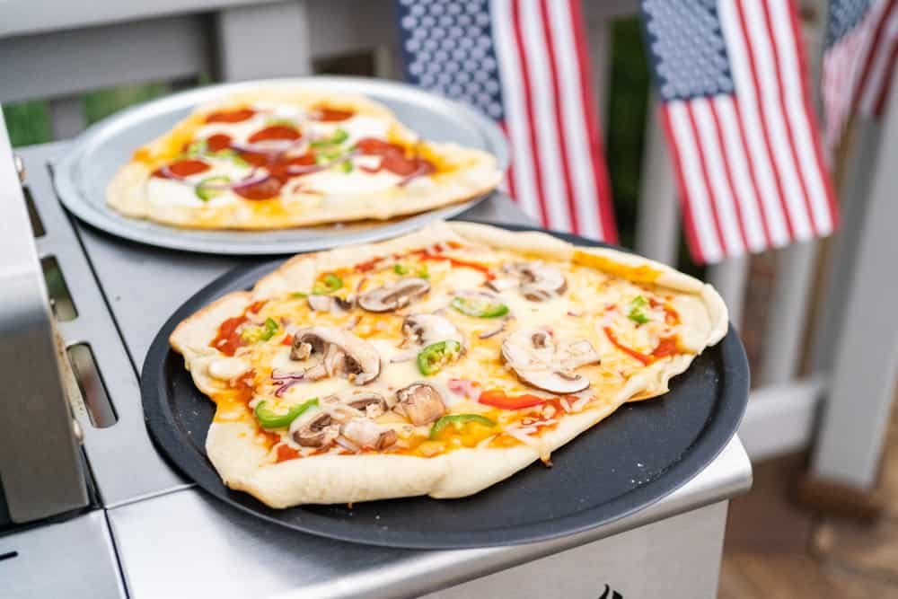 Preparing individual grilled pizzas on an outdoor gas grill