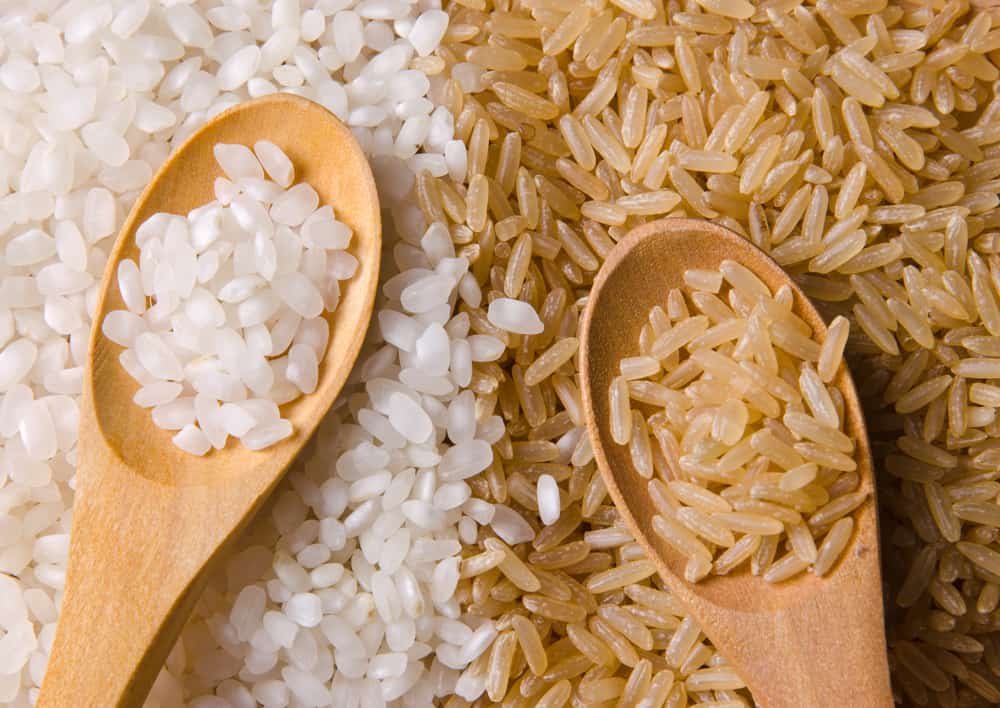 Natural white and brown long rice in wood spoons